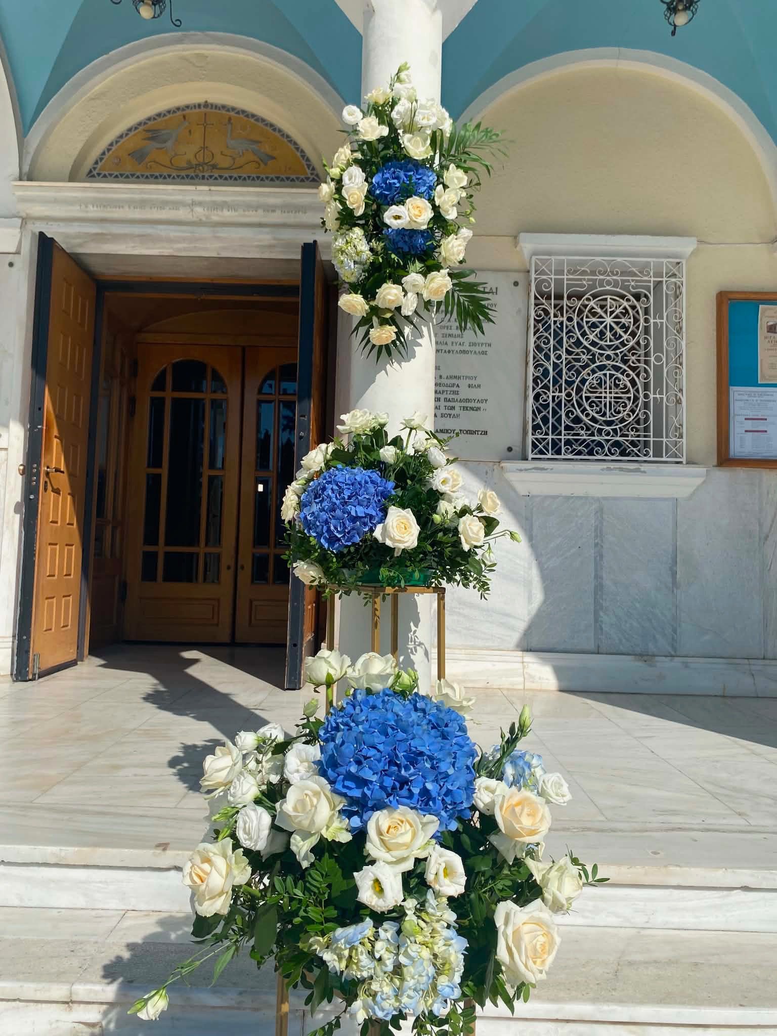Λεπτομέρεια στολισμού κολόνας με λευκά τριαντάφυλλα και μπλε ορτανσίες